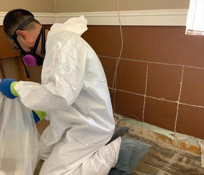 worker kneeling and holding a trash bag